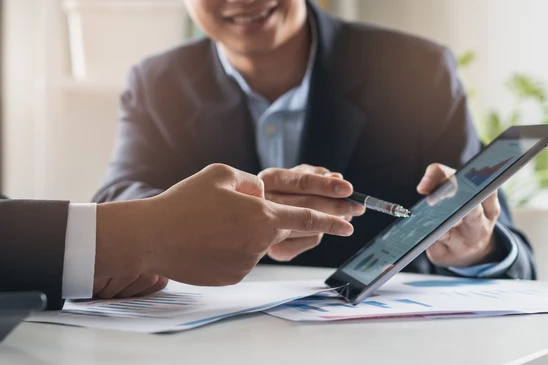 Deux professionnels en costume analysent des données financières dans un bureau lumineux