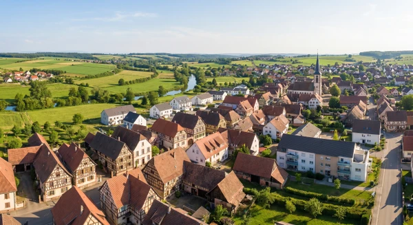 Vue panoramique de la localité de Hochfelden en Alsace, montrant un paysage urbain ou rural typique de la région du Bas-Rhin avec des bâtiments résidentiels et commerciaux, dégageant une atmosphère de petite commune de proximité accessible et accueillante. La photo doit être prise de jour avec un bon éclairage naturel.