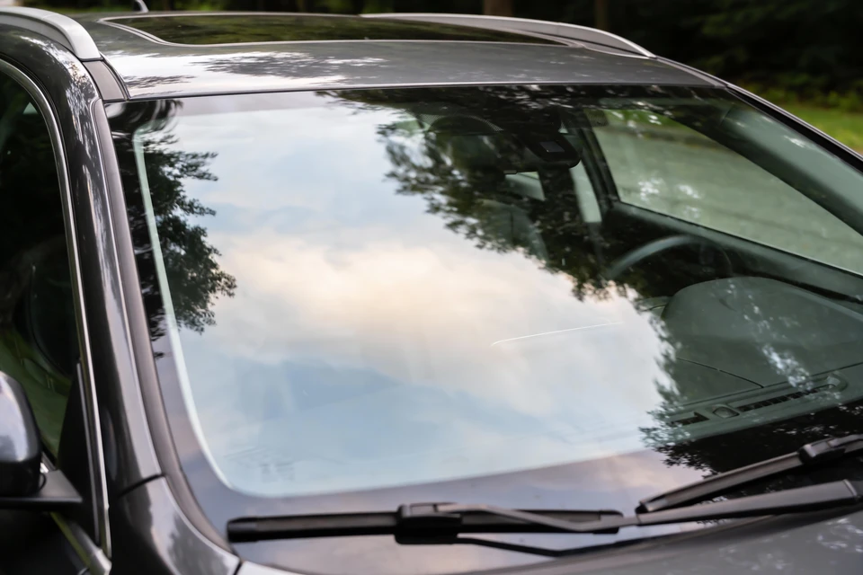 Intérieur de véhicule automobile vu à travers le pare-brise, siège conducteur occupé par une personne, habitacle moderne avec tableau de bord visible