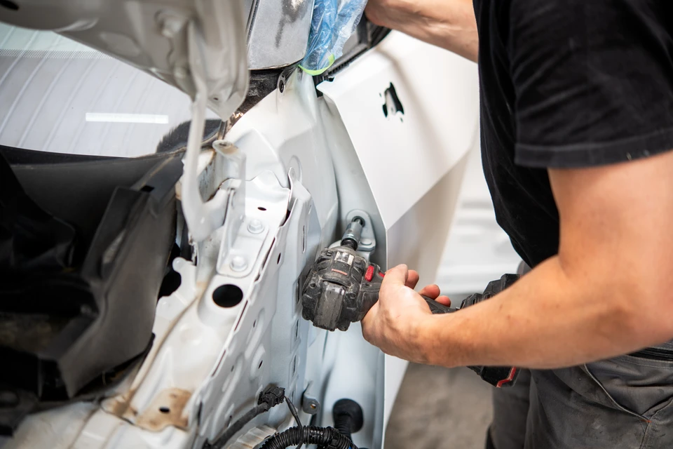 Atelier de carrosserie automobile avec technicien réparant une carrosserie blanche