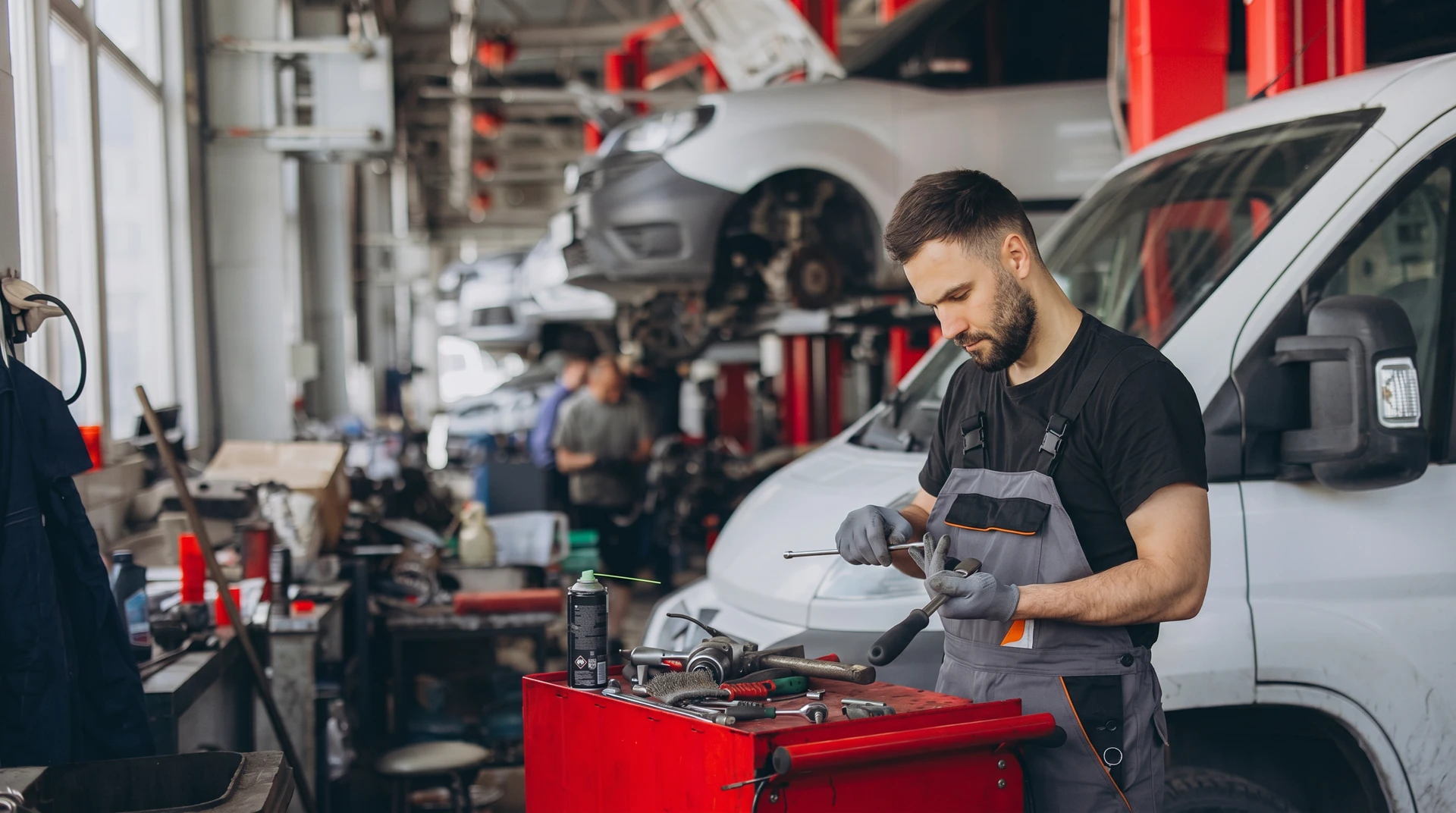 Mécanicien automobile travaillant sous le capot ouvert d'un véhicule, utilisant des outils de réparation dans un garage